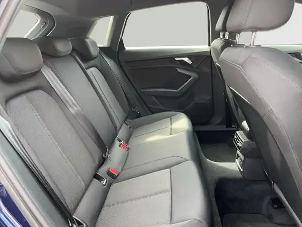 Das Bild zeigt den Innenraum eines Audi A3 Sportback, konkret die Rückbank mit schwarzem Interieur.