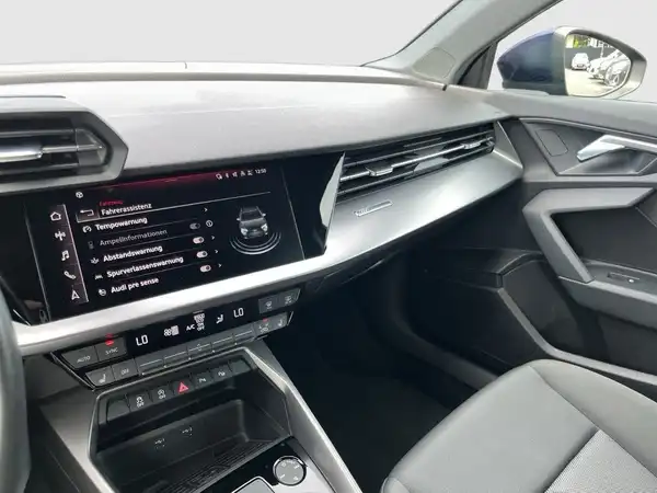 Das Bild zeigt das Innenraumdisplay eines AUDI A3 SPORTBACK mit verschiedenen Funktionen wie Fahrassistenz und Tempowarnung.