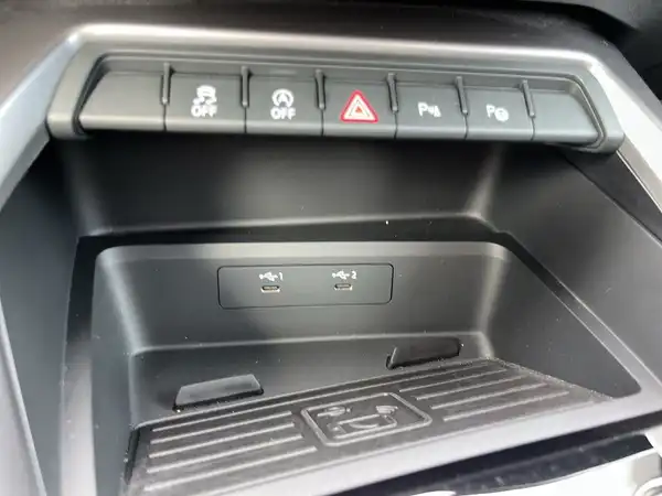 Das Bild zeigt das Innenleben eines Audi A3 Sportback mit einer Nahansicht der Steuerknöpfe und Ablagefläche in Schwarz.