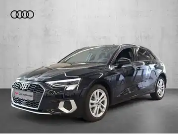 Das Bild zeigt einen schwarzen AUDI A3 SPORTBACK von der Seite. Im Hintergrund ist ein grauer Wandanstrich zu sehen, und es gibt ein Händlerlogo oben im Bild.