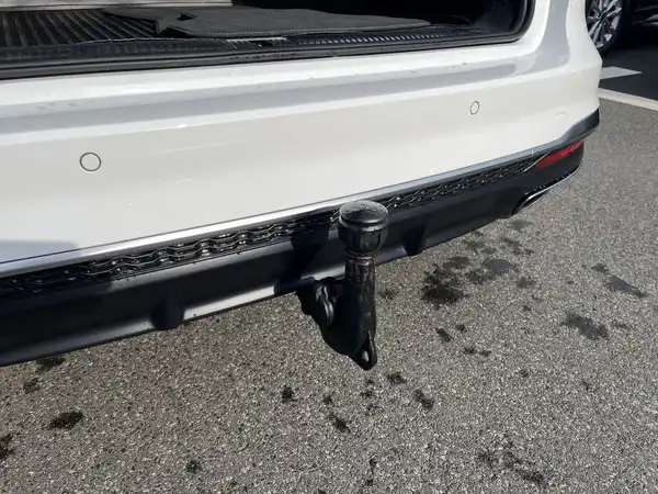 Das Bild zeigt die Rückansicht eines weißen AUDI A4 AVANT mit einem Sicht auf die Anhängerkupplung.