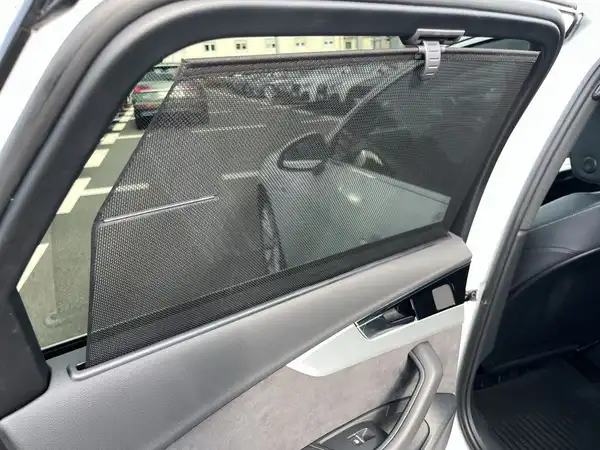 Eine Innenaufnahme des Fahrzeugs, die eine Seitenfensterblende zeigt, darauf sind weitere Fahrzeuge im Hintergrund zu sehen.