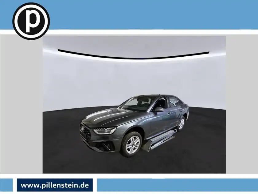 Das Bild zeigt einen grauen AUDI A4 LIMOUSINE von der Seite. Im Hintergrund ist ein schlichtes Studio-Setup zu sehen. Auf dem Bild ist das Händlerlogo zu erkennen sowie eine markante Texteinblendung.