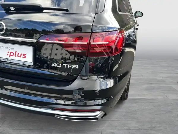 Ansicht des Fahrzeugs von hinten, es handelt sich um einen schwarzen Audi A4 Avant. Das Händlerlogo ist sichtbar, ebenso wie die Typenbezeichnung "40 TFSI".