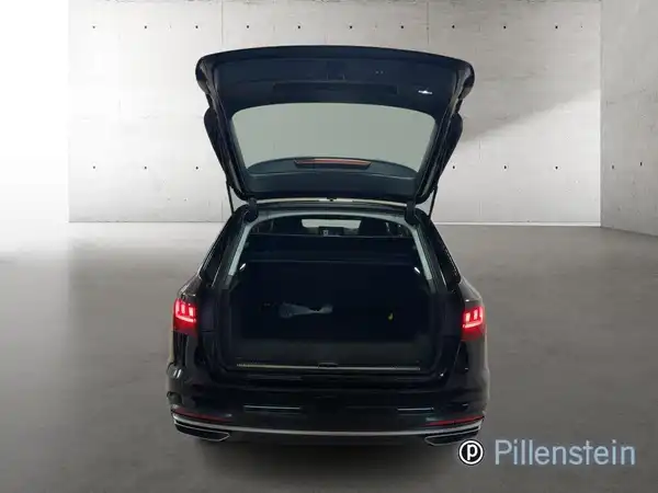 Das Bild zeigt die Rückansicht eines schwarzen Audi A4 Avant mit offenem Kofferraum. Im Hintergrund ist eine graue Wand zu sehen, wobei das Händlerlogo "Pillenstein" eingeblendet ist.