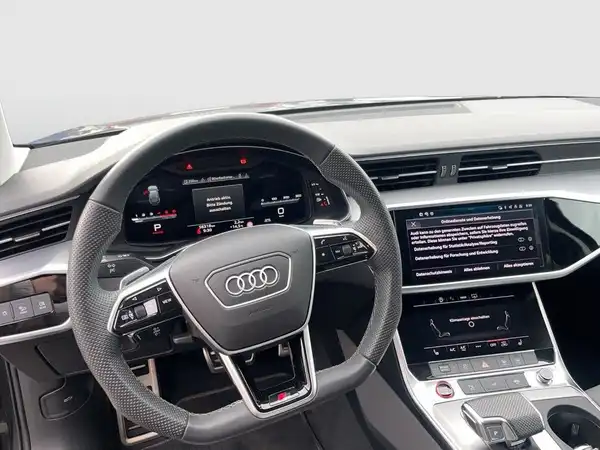 Innenaufnahme des Audi S6 Avant mit schwarzem Interieur. Es sind markante Texteinblendungen auf dem Bildschirm sichtbar.