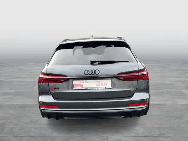 Ein Bild des Audi S6 Avant von hinten in grauer Farbe. Das Händlerlogo ist sichtbar, und es gibt markante Texteinblendungen.