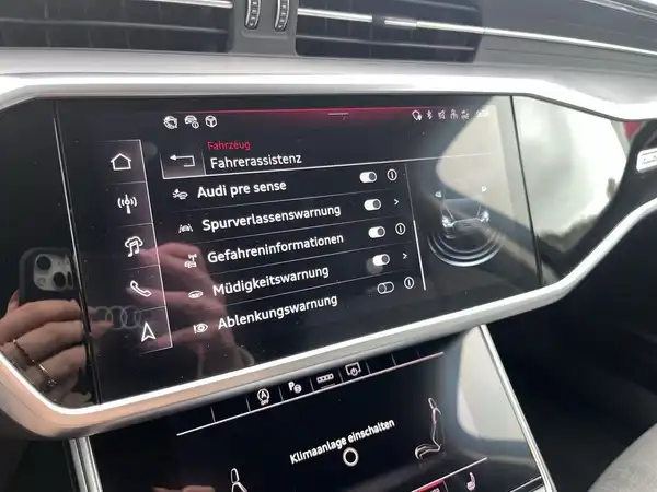 Das Bild zeigt das Innere eines Audi S6 Avant mit einem schwarzen Interieur. Auf dem Display sind verschiedene Fahrerassistenzsysteme angezeigt.