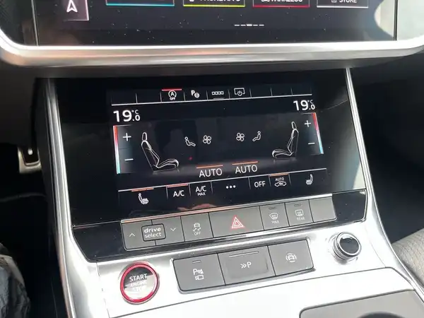 Das Bild zeigt das Innenraumdisplay eines AUDI S6 AVANT mit Bedienelementen für die Klimaanlage und weiteren Funktionen. Die Innenfarbe ist schwarz.