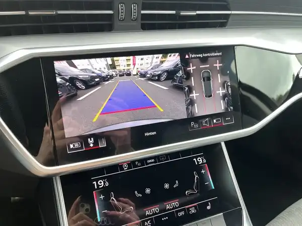 Das Bild zeigt das Interieur eines AUDI S6 AVANT mit einem Navigations- und Kamerasystem auf dem Bildschirm. Die Innenausstattung ist schwarz.