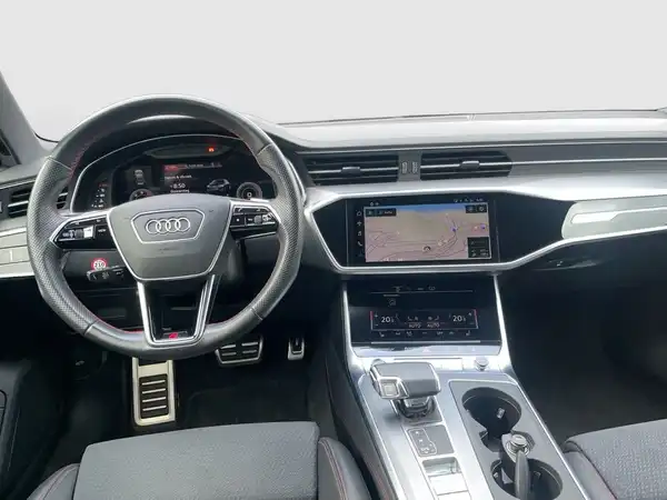 Das Bild zeigt das Innere eines AUDI A6 mit schwarz gestaltetem Interieur. Es enthält markante Texteinblendungen.
