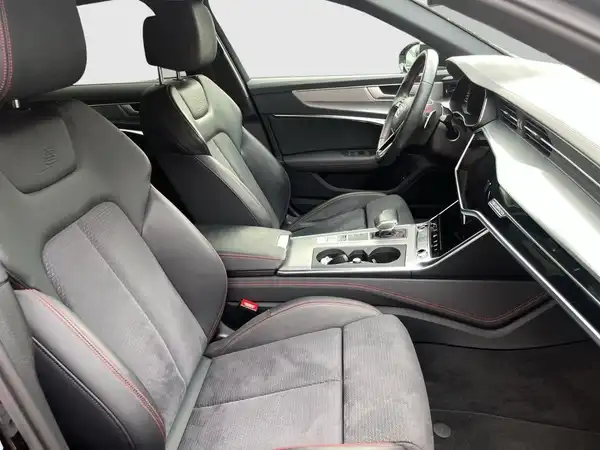 Das Bild zeigt den Innenraum eines AUDI A6 mit schwarzen Sitzen und roten Akzenten.