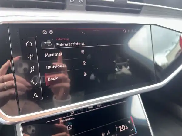 Die Innenaufnahme zeigt das Infotainment-System des Fahrzeugs mit einem Fokus auf die Fahrerassistenz-Einstellungen. Die Interieurfarbe ist schwarz.