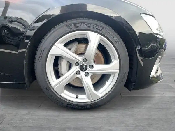 Dieses Bild zeigt die Seite eines schwarzen AUDI A6, fokussiert auf das Rad und die Felge.