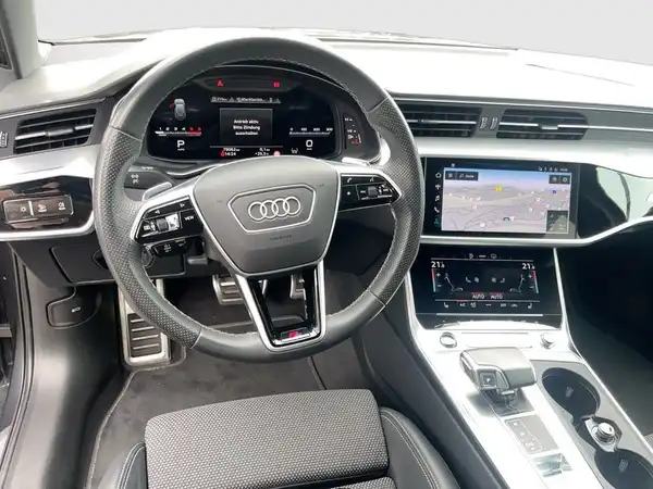 Das Bild zeigt das Innere eines AUDI A6 AVANT, aufgenommen aus der Perspektive des Fahrers. Das Interieur ist in schwarzer Farbe gehalten.