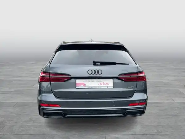 Das Bild zeigt einen grauen Audi A6 Avant von hinten, mit einem eingeblendeten Händlerlogo und markanten Texteinblendungen.