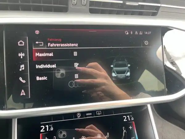 Eine Innenaufnahme des Fahrzeugs zeigt das Infotainment-System mit einer Übersicht der Fahrerassistenzfunktionen und einer Darstellung des Fahrzeugs auf dem Bildschirm.