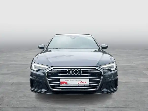 Das Bild zeigt einen schwarzen Audi A6 Avant von vorne. Es enthält ein Händlerlogo und markante Texteinblendungen.