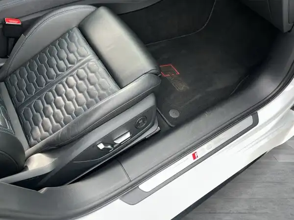 Das Bild zeigt den Innenraum eines AUDI RS6 AVANT mit einem schwarzen Sitz und einem weißen Exterieur.