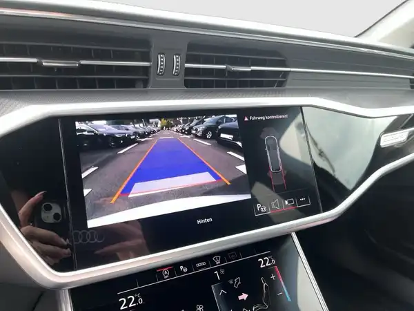 Das Bild zeigt das Innere eines AUDI RS6 AVANT mit einem Bildschirm, der eine Rückfahrsichtkamera anzeigt. Der Bildschirm hat eine grafische Darstellung des Abstands und eine Textanzeige für die Rückfahrhilfe.