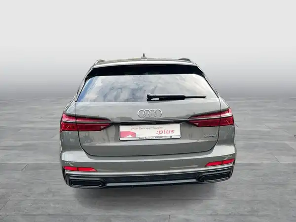 Das Bild zeigt den hinteren Blickwinkel eines grauen AUDI A6 AVANT. Es sind markante Texteinblendungen und ein Händlerlogo vorhanden.