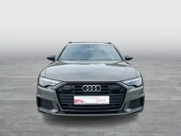 Das Bild zeigt einen grauen Audi A6 Avant von vorne. Es enthält ein Händlerlogo und markante Texteinblendungen.