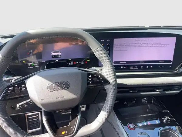 Das Bild zeigt das Innere eines AUDI A6, aufgenommen vom Fahrersitz aus. Der Innenraum ist schwarz und modern gestaltet.