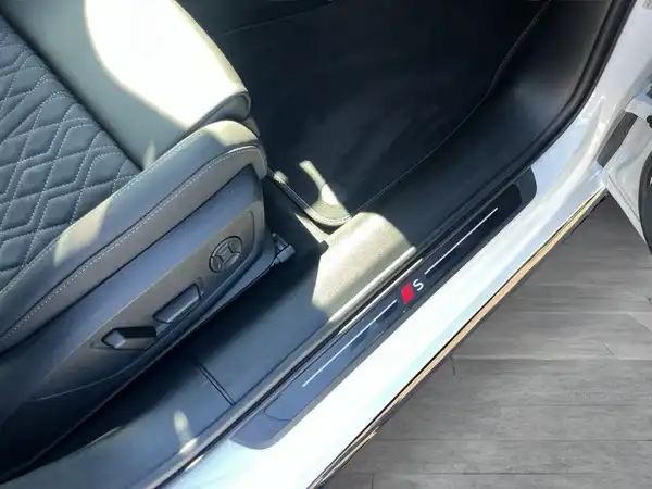 Das Bild zeigt den Innenbereich eines weißen Audi A6 Avant mit schwarzer Sitzausstattung. Die Aufnahme zeigt die Verbindung zwischen Sitz und Tür.