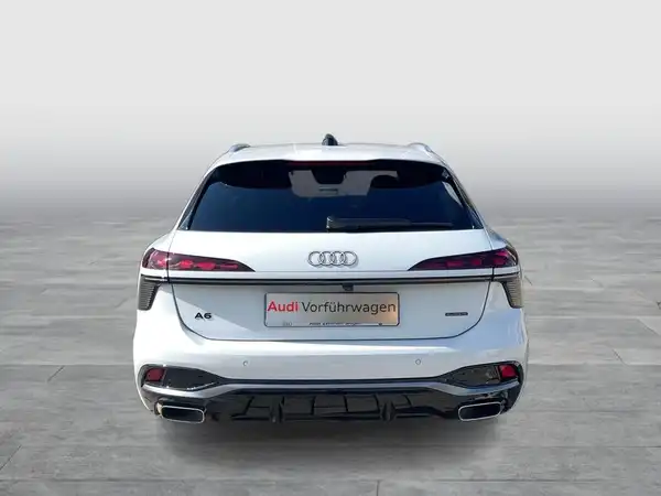 Das Bild zeigt einen weißen AUDI A6 AVANT von hinten. Es enthält ein Händlerlogo und eine markante Texteinblendung.
