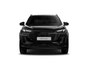 Das Bild zeigt einen schwarzen AUDI Q6 e-tron aus der Frontansicht. Es gibt markante Texteinblendungen auf dem Bild.