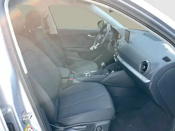 Das Bild zeigt das Innere eines Fahrzeugs, einen AUDI Q2, mit schwarzen Sitzen und Armaturen.