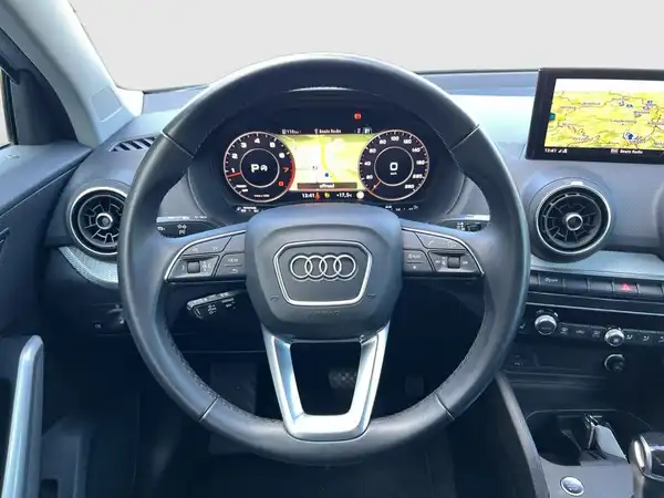 Das Bild zeigt das Innenraum des AUDI Q2 mit einem schwarzen Interieur und einer Anzeige auf dem Touchscreen.