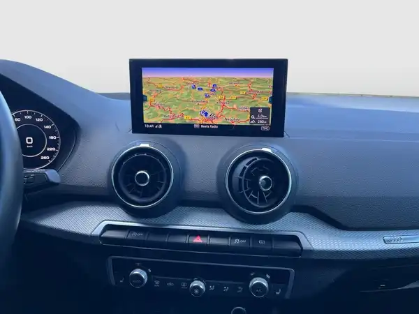 Das Bild zeigt das Innere eines AUDI Q2 mit einem Navigationsgerät und einer modernen, sportlichen Innenausstattung in Schwarz.