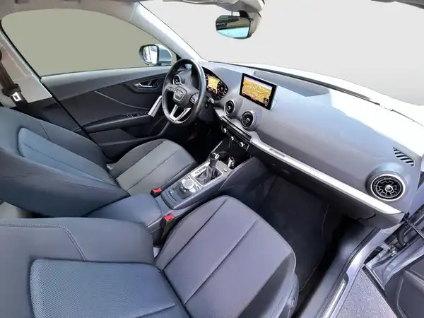 Das Bild zeigt den Innenraum eines AUDI Q2, hauptsächlich mit schwarzen Sitzen und einem modernen Armaturenbrett.