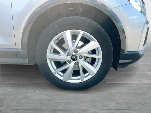 Das Bild zeigt die Seite eines silbernen AUDI Q2 mit Fokus auf dem Reifen und der Felge.