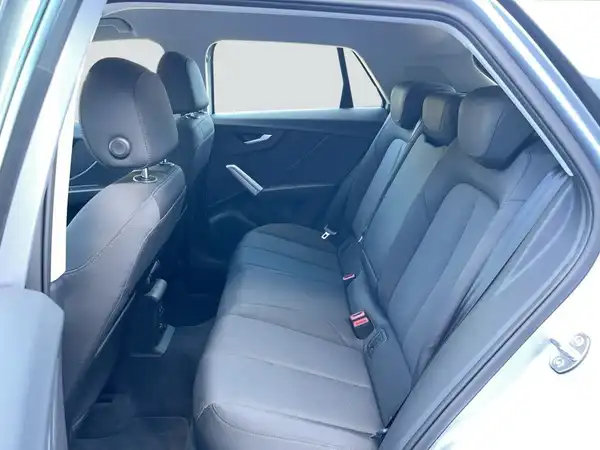 Das Bild zeigt den Innenraum eines AUDI Q2 aus der Rückansicht. Die Sitze sind schwarz und aus Stoff.