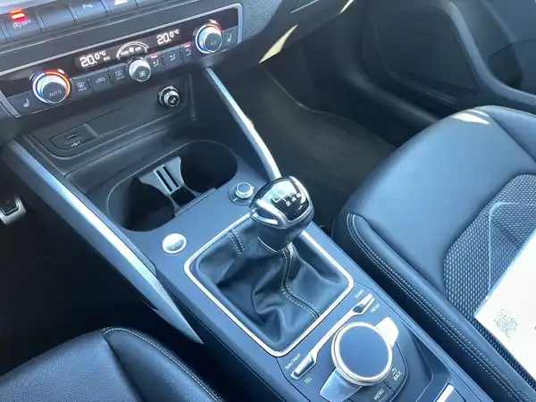 Das Bild zeigt den Innenraum eines Fahrzeugs, aus dem Blickwinkel der Mittelkonsole. Das Interieur ist in Schwarz.