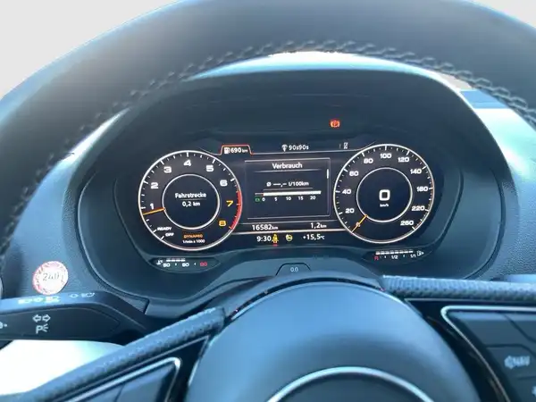 Das Bild zeigt das Innenraum-Display eines AUDI Q2, aufgenommen von innen. Das Interieur ist schwarz und es sind markante Texteinblendungen auf dem Display zu sehen. Es handelt sich um eine Innenaufnahme.
