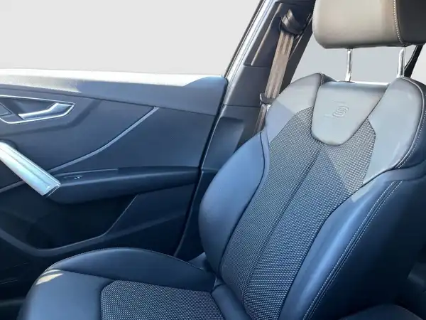 Das Bild zeigt den Innenraum des AUDI Q2, insbesondere den Fahrersitz, der in schwarz mit Netztextur gestaltet ist.