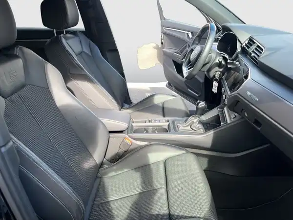 Eine Innenaufnahme des Audi Q3 mit schwarzen Sitzen und einem modernen Armaturenbrett.