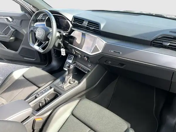 Das Bild zeigt das Innere eines AUDI Q3 mit schwarzem Interieur, das aus einer Mischung von Stoff und Leder besteht.