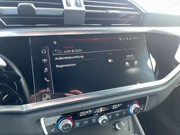Innenaufnahme des AUDI Q3 mit einem schwarzen Innenraum und markanten Texteinblendungen auf dem Bildschirm.