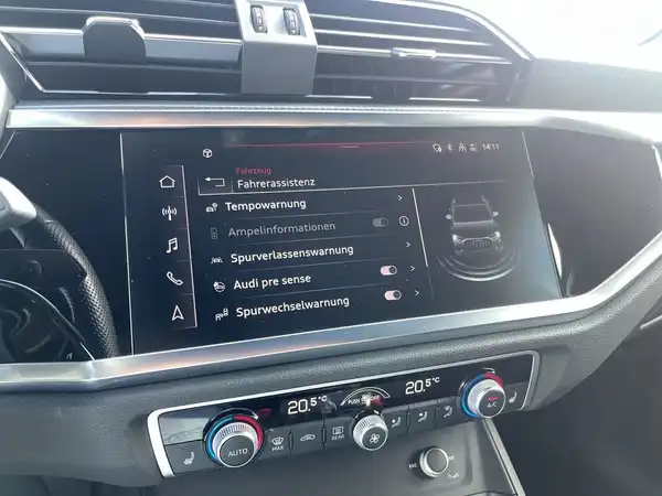 Innenaufnahme des Fahrzeugs AUDI Q3 mit schwarzem Interieur und markanten Texteinblendungen auf dem Bildschirm.