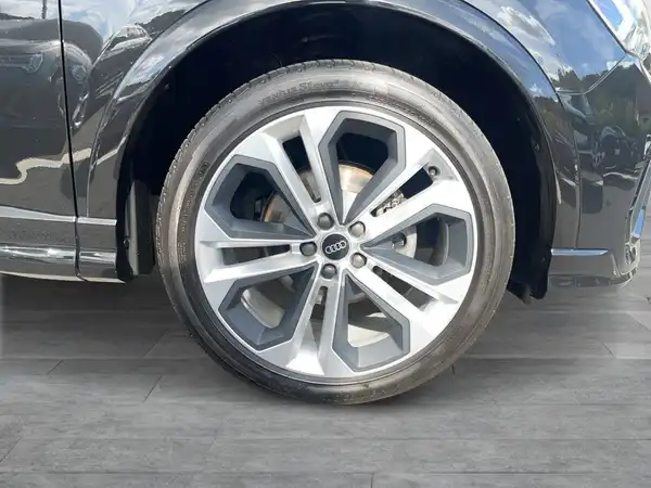 Das Bild zeigt die Seite eines AUDI Q3, speziell einen Teil des Rads mit einer silbernen Felge.