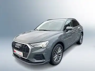 Das Bild zeigt einen grauen Audi Q3 aus der Frontansicht. Es enthält das Händlerlogo von Audi Zentrum Siegen sowie Werbetexte zu Gebrauchtwagen.