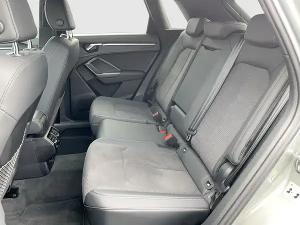 Das Bild zeigt den Innenraum des Audi Q3, insbesondere die Rücksitze in schwarzer Farbgebung. Es handelt sich um eine Innenaufnahme des Fahrzeugs.