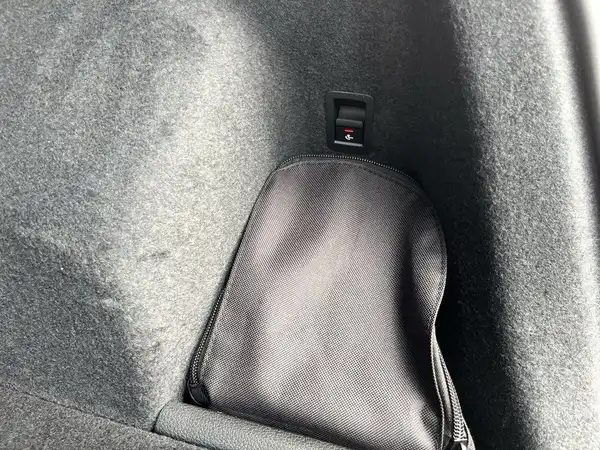Das Bild zeigt das Innere des Kofferraums eines Fahrzeugs, auf dem eine schwarze Tasche zu sehen ist.