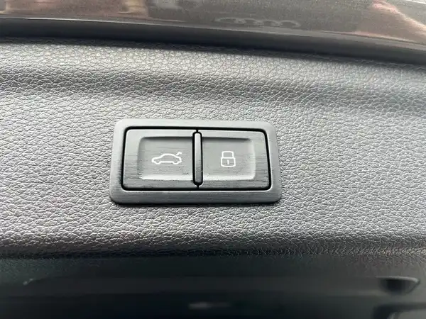 Das Bild zeigt die Innenansicht eines Audi Q3 mit einem Fokus auf Tasten für Fenster und Zentralverriegelung. Das Interieur ist in schwarz.