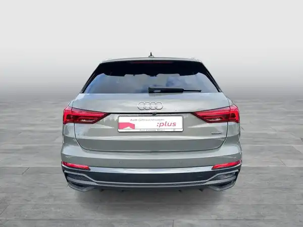 Das Bild zeigt einen grauen Audi Q3 von hinten. Im Hintergrund ist eine graue Fläche zu sehen.