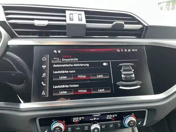 Das Bild zeigt den Innenraum eines Audi Q3 mit einer zentralen Anzeige. Die Farbe des Interieurs ist schwarz und es gibt markante Texteinblendungen auf dem Bildschirm.